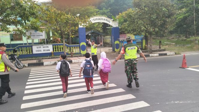 
					Babinsa bersama Bhabinkamtibmas Karangpanimbal Polsek Purwaharja kompak Sebrangkan Pelajar SD 